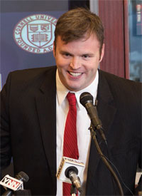 David Archer '05 at a mike during a press conference