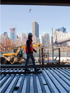 A worker walks across a floor, with Manhattan in the background