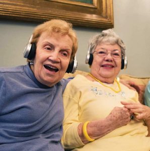 Two elderly women use the Eversound headphones.