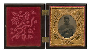 An open book tintype with red velvet embossed on the left, and black and white image of a soldier holding a pistol