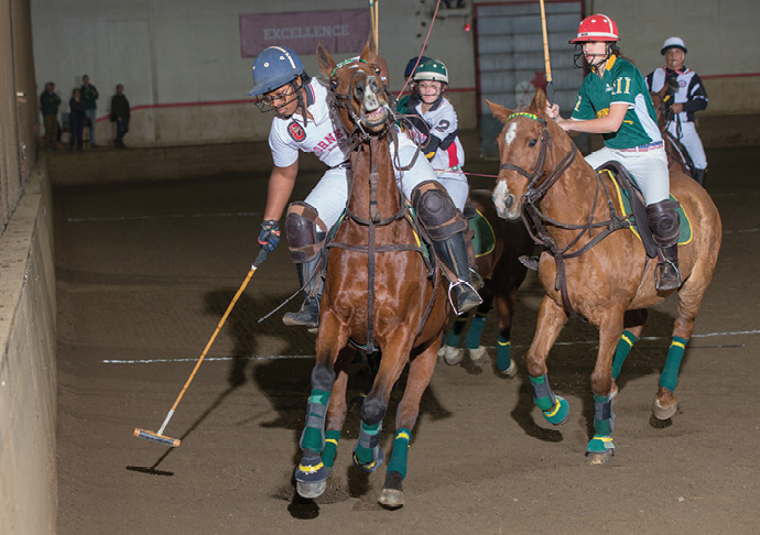 Polo players vie for the ball in an indoor arena during a match.
